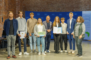 Sechs Schülerinnen und Schüler und zwei Lehrkräfte des Gymnasiums Landschulheim Marquartstein posieren mit Herrn Staatsminister Glauber und Ihrer Urkunde.